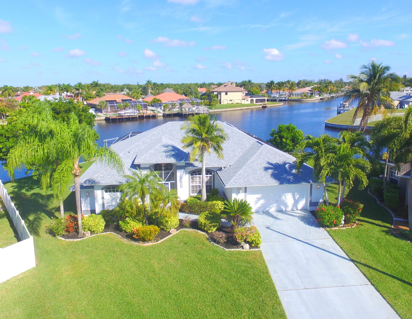 aerial view of large home with landscaping and grass yard by water